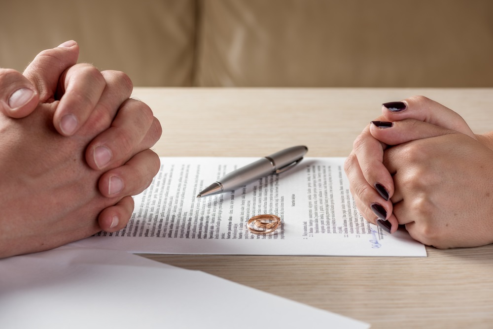 Hands of wife and husband signing divorce