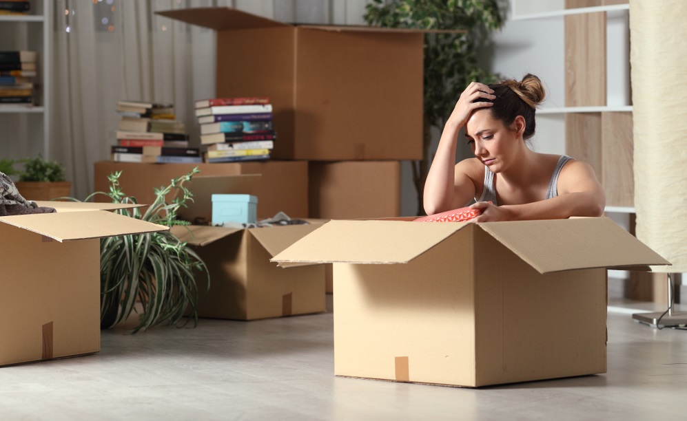 Sad evicted tenant moving home boxing belongings sitting on the floor in the night